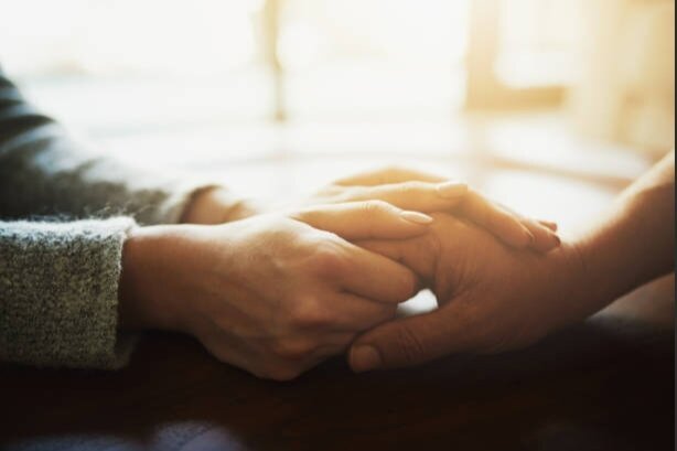 Two people holding hands across a table